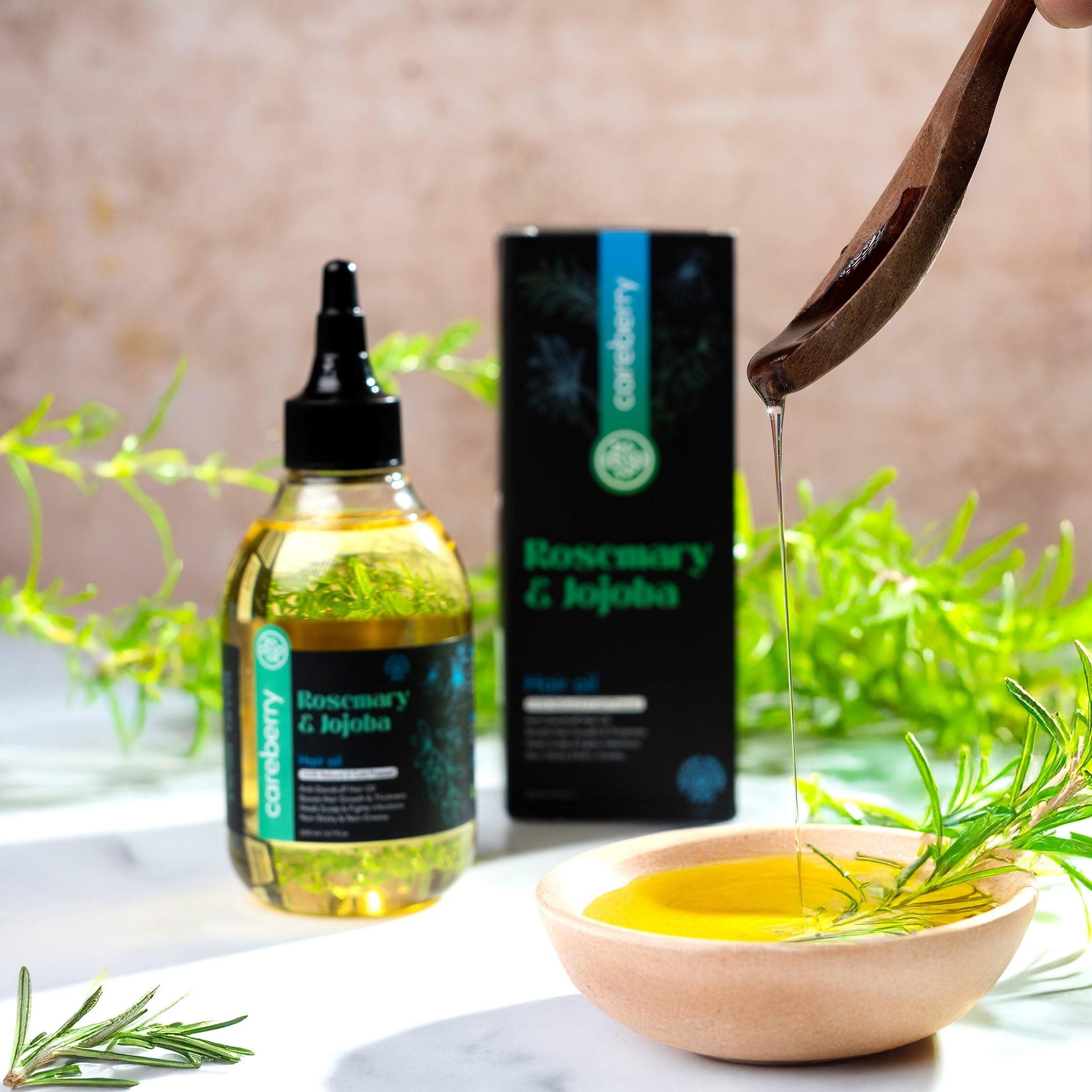 Rosemary and Jojoba hair oil dripping into bowl with fresh rosemary for scalp care
